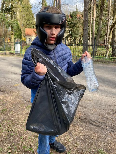młody chłopak w kasku i trzymający plastikową torbę.