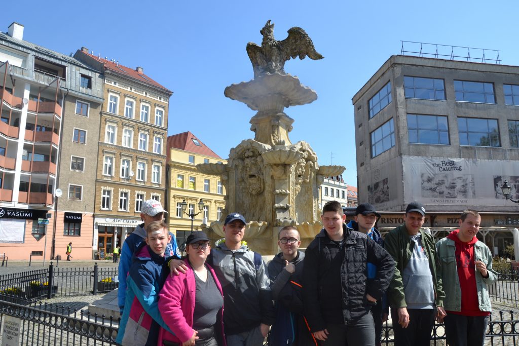 grupa ludzi stojących przed fontanną.
