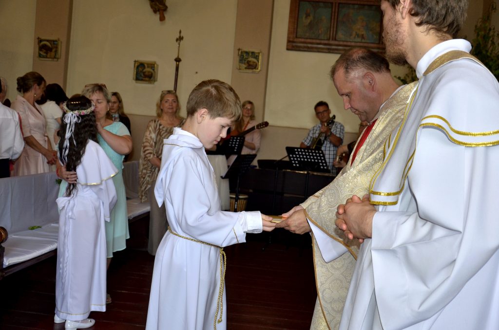 mężczyzna w stroju księdza ściskający dłoń chłopcu w księdzu.