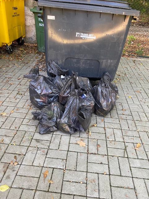 stos worków na śmieci leżący na chodniku.