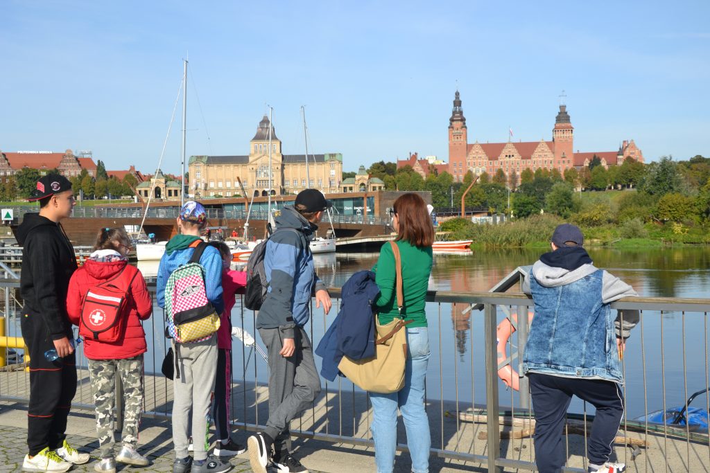 grupa ludzi stojących na moście nad zbiornikiem wodnym.