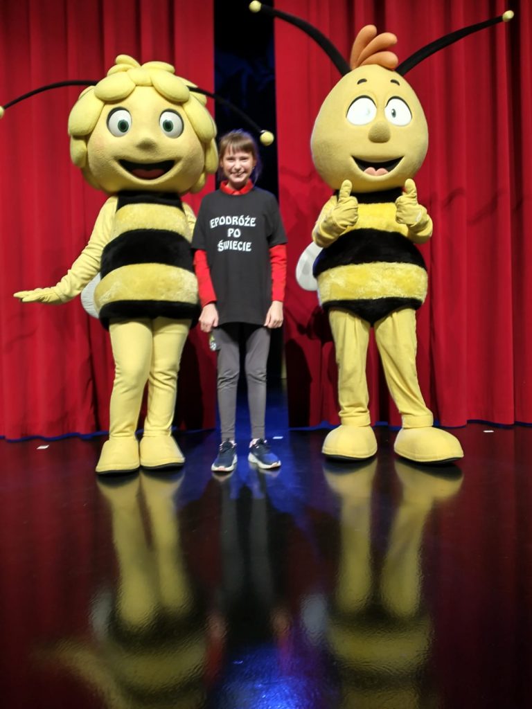 osoba stojąca przed maskotką dwóch pszczół.