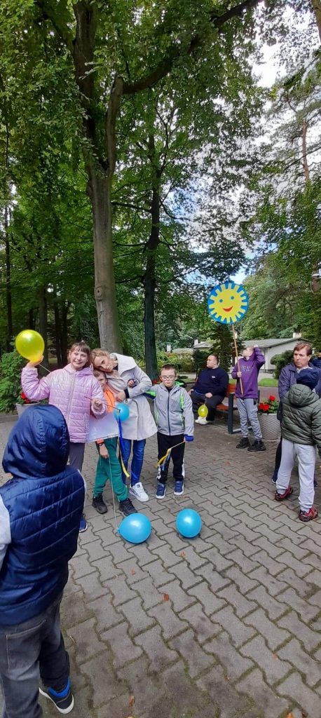 grupa dzieci bawiących się balonami w parku.