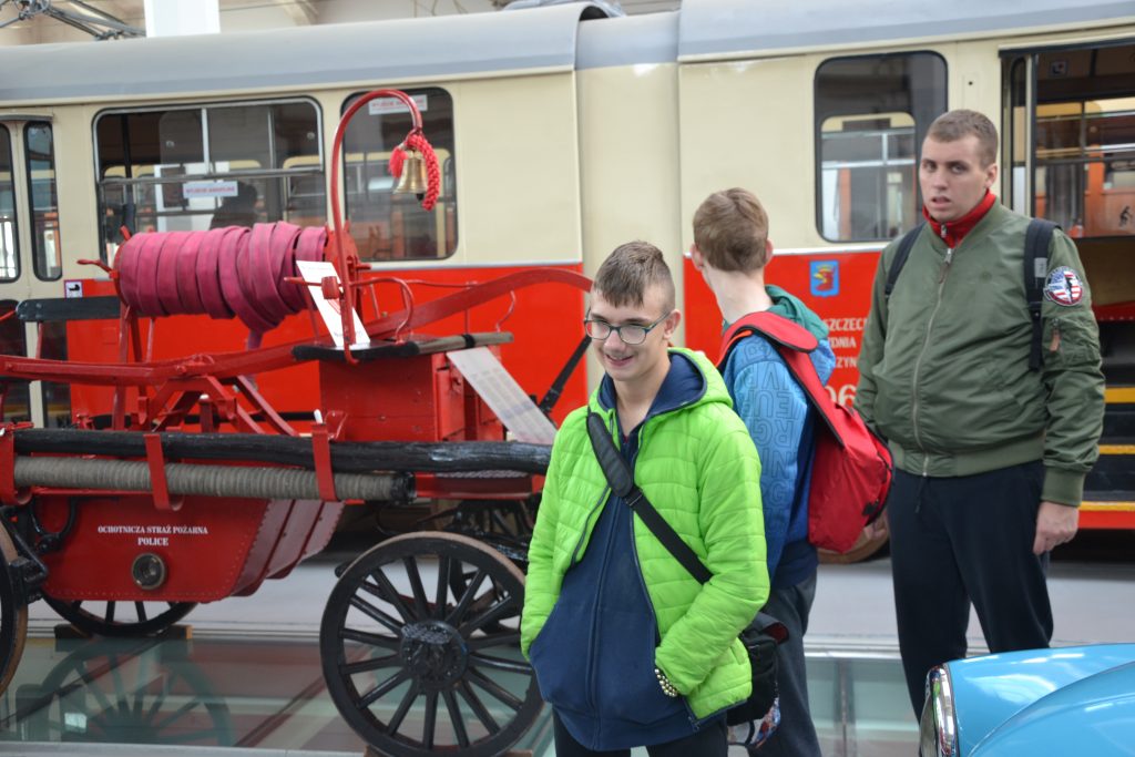 grupa ludzi stojących obok czerwono-białego pociągu.