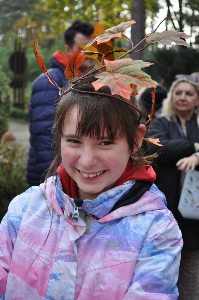młoda dziewczyna ubrana w nakrycie głowy z liścia w parku.