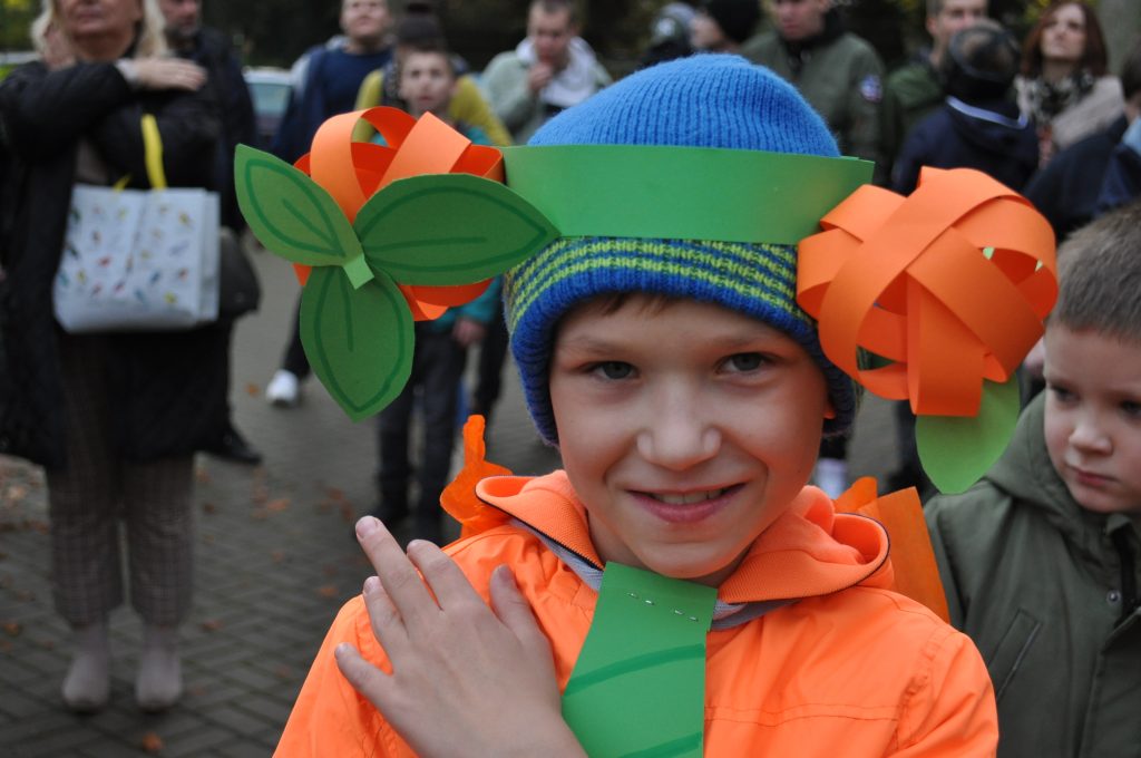 młody chłopak w zielonym kapeluszu i pomarańczowej kurtce.