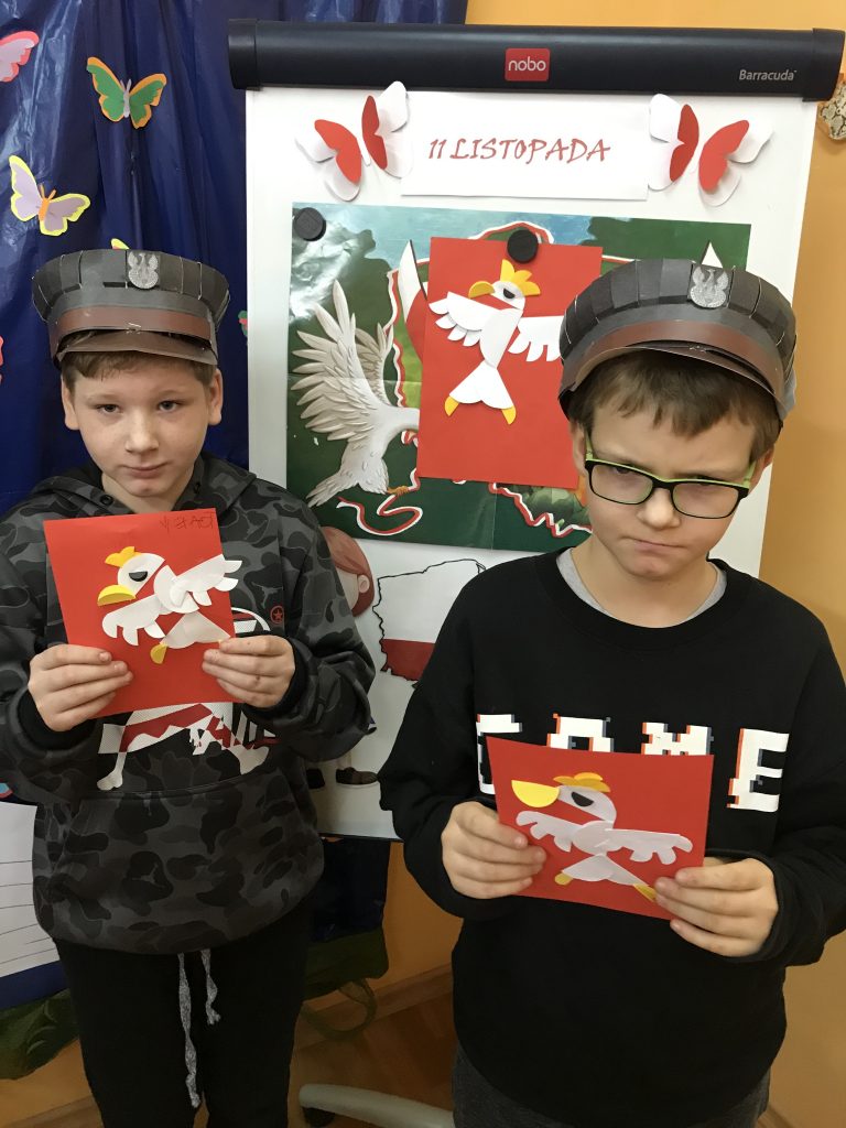 dwóch młodych chłopców w papierowych kapeluszach i trzymających karty.