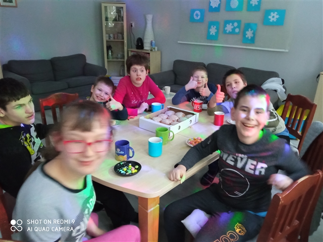 grupa dzieci siedzących wokół stołu.