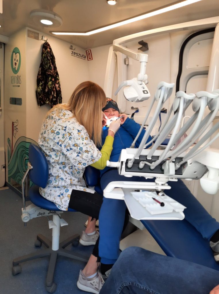 kobieta siedząca na fotelu dentystycznym z otwartymi ustami.