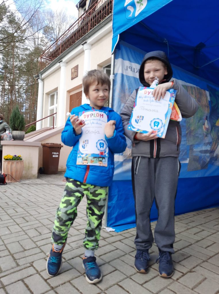 dwóch młodych chłopców trzyma znaki przed niebieskim namiotem.