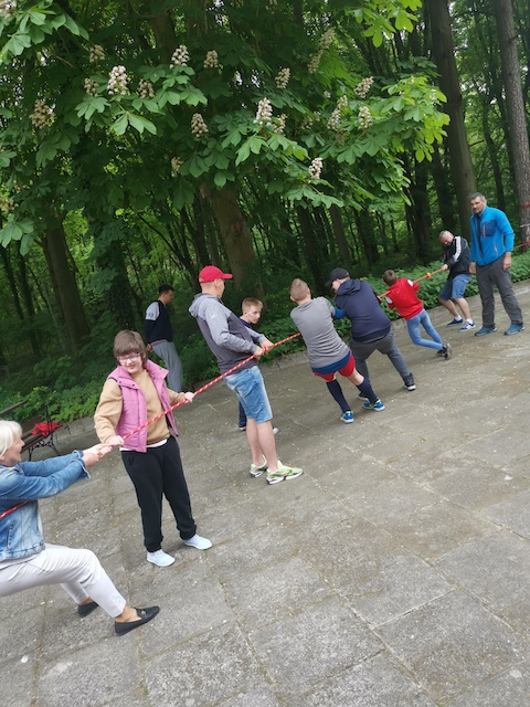 grupa ludzi grających w przeciąganie liny w parku.