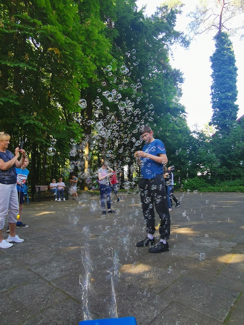 grupa ludzi bawiących się bąbelkami w parku.