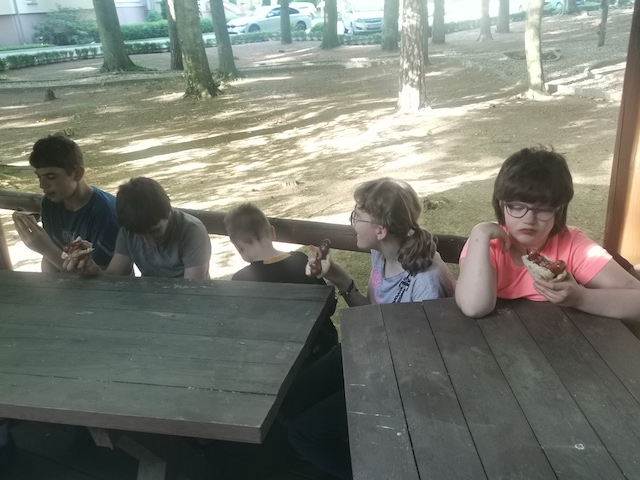 grupa dzieci siedzących przy stole piknikowym.