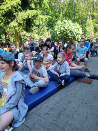 grupa dzieci siedzących na niebieskiej macie.