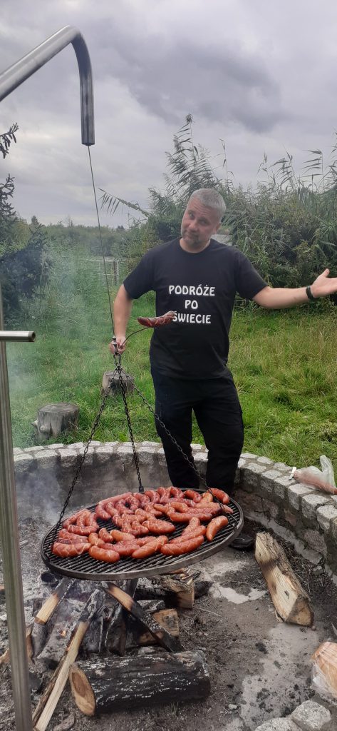 mężczyzna gotuje hot dogi na grillu.