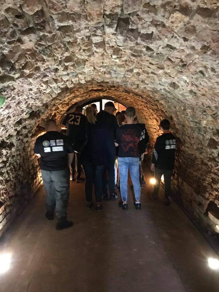 grupa ludzi idących przez tunel.