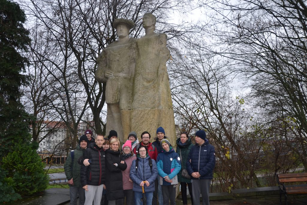 grupa ludzi stojących przed pomnikiem.