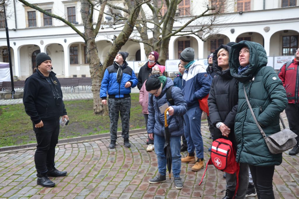 grupa ludzi stojących na ceglanym chodniku.