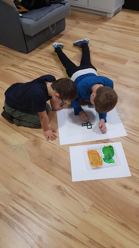 dwóch młodych chłopców bawiących się papierem na podłodze.