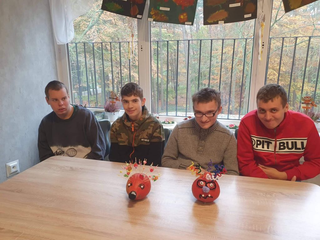grupa młodych mężczyzn siedzących przy drewnianym stole.