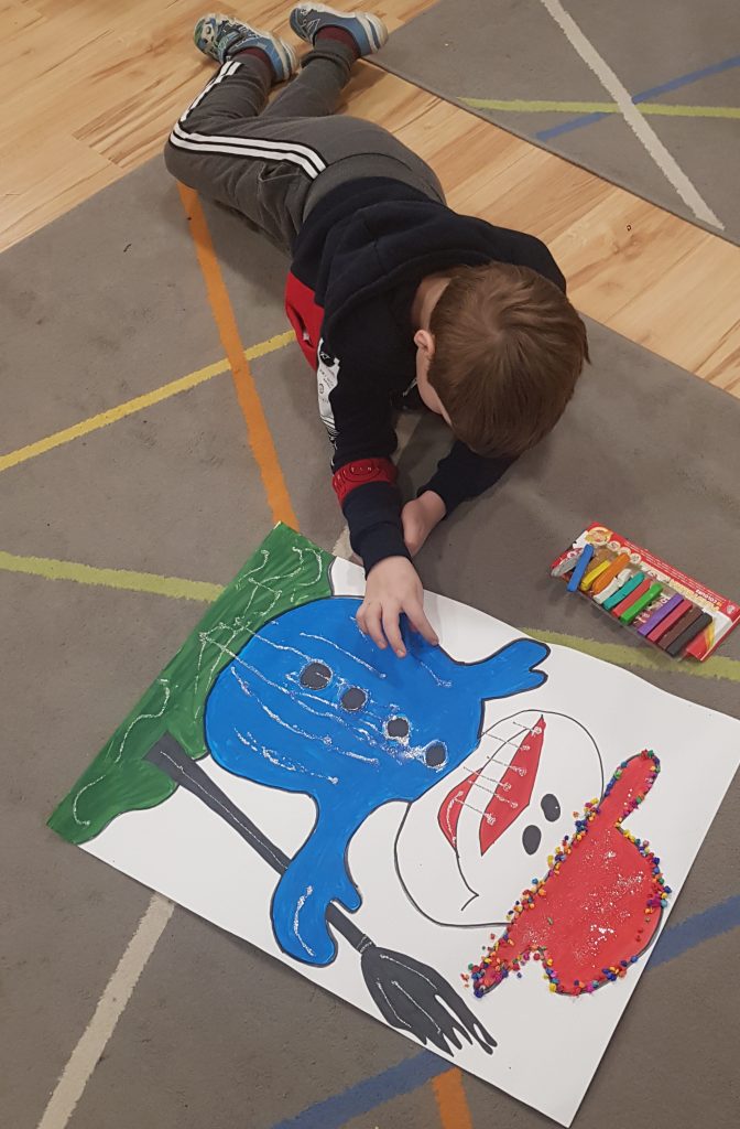 młody chłopak leżący na podłodze rysuje obrazek.