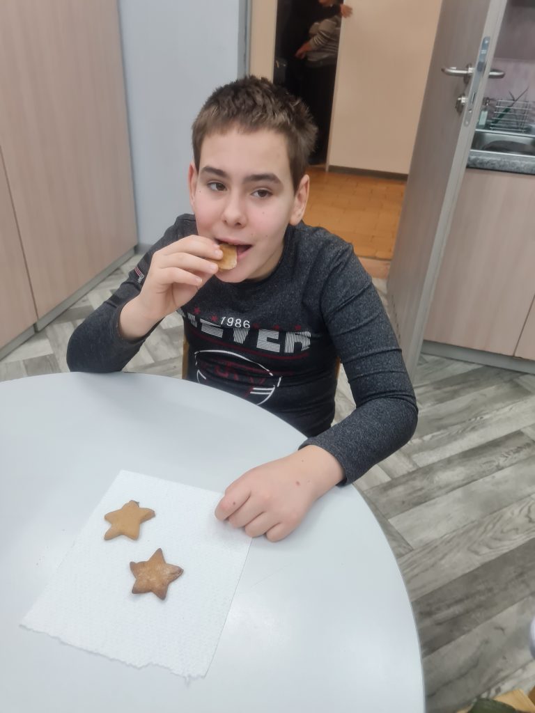 młody chłopak siedzi przy stole i je ciastko.