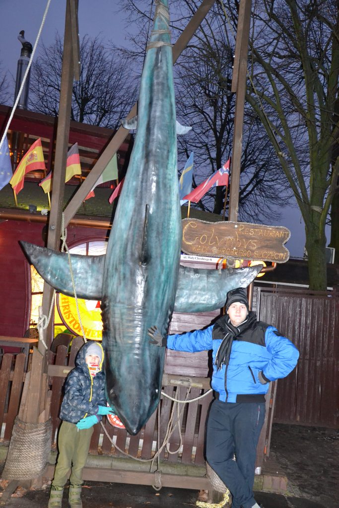 dwie osoby stojące obok posągu rekina.