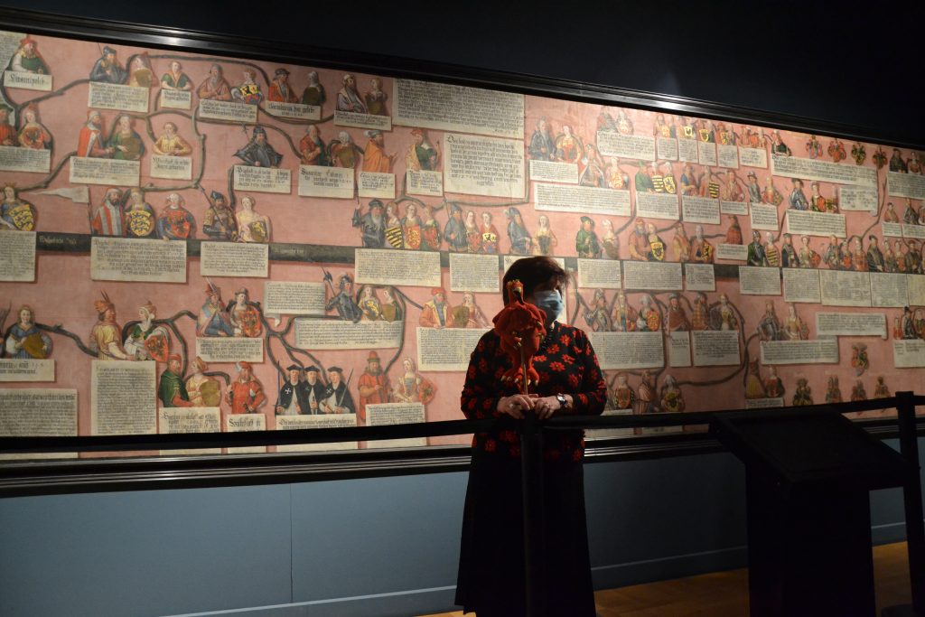 kobieta stojąca przed ścianą pokrytą obrazami.