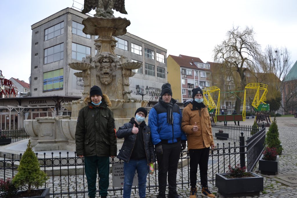 grupa ludzi stojących przed fontanną.