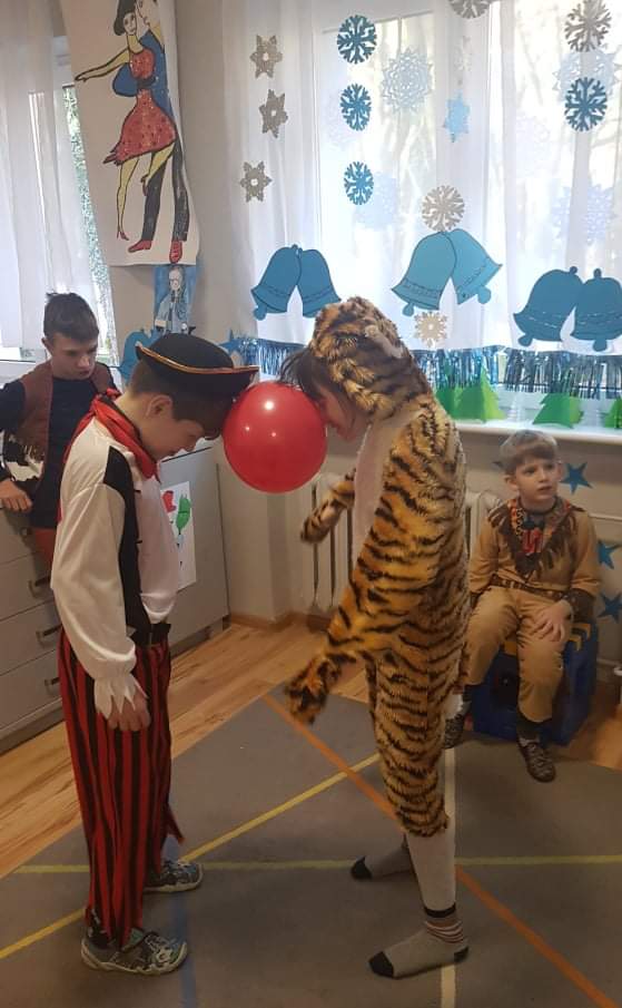 dwoje dzieci w kostiumach bawi się tygrysem.
