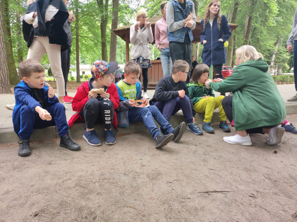 grupa dzieci siedzi na ławce w parku.