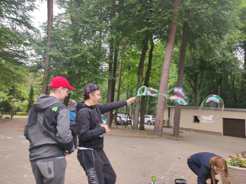 grupa ludzi dmuchających bańki w parku.