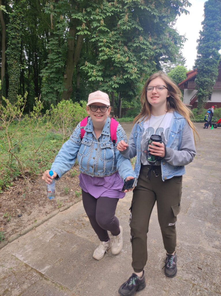 dwie kobiety idące leśną ścieżką.