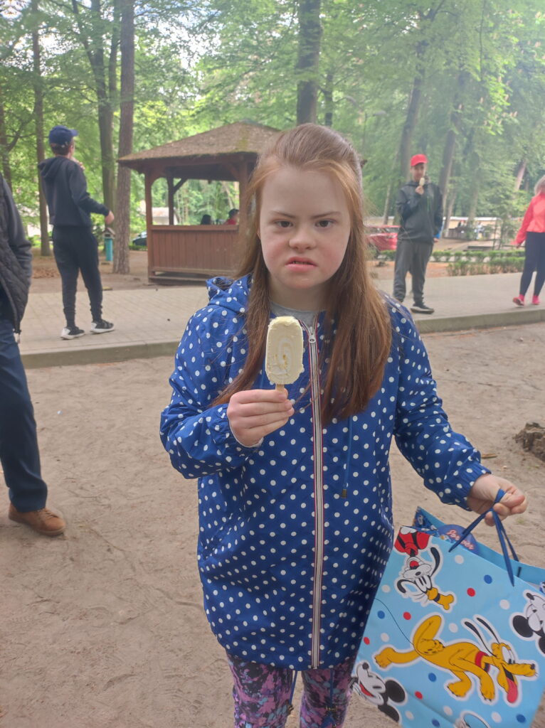 mała dziewczynka trzyma lizaka w parku.