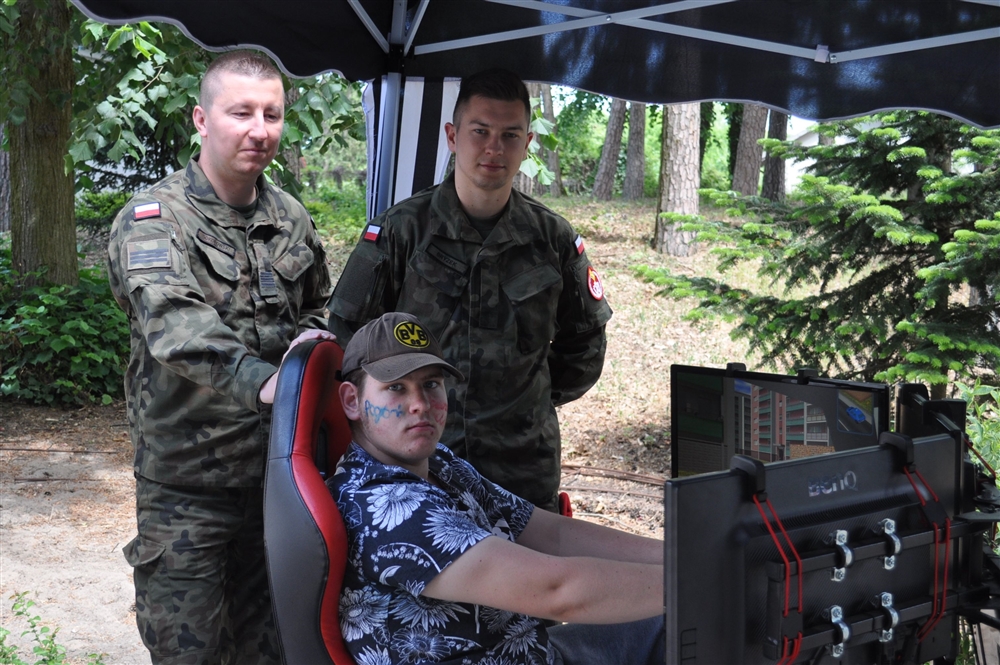 Dwóch wojskowych stojących przy mężczyźnie siedzącym przed monitorami