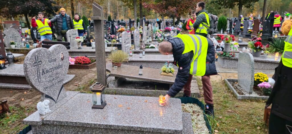 Uczniowie zapalają znicze na cmentarzu 