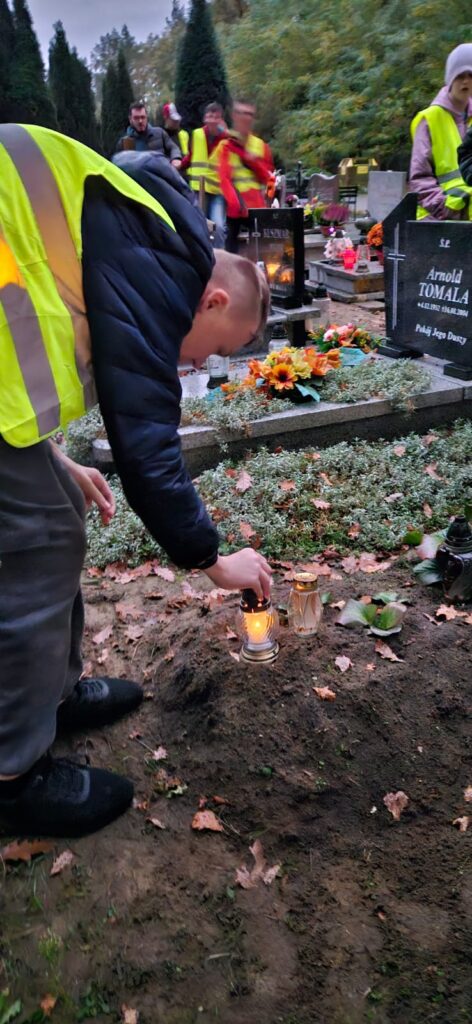 Uczniowie zapalają znicze na cmentarzu 