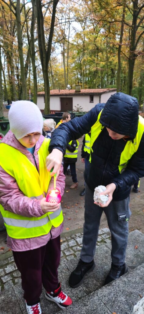 Uczniowie zapalają znicze na cmentarzu 