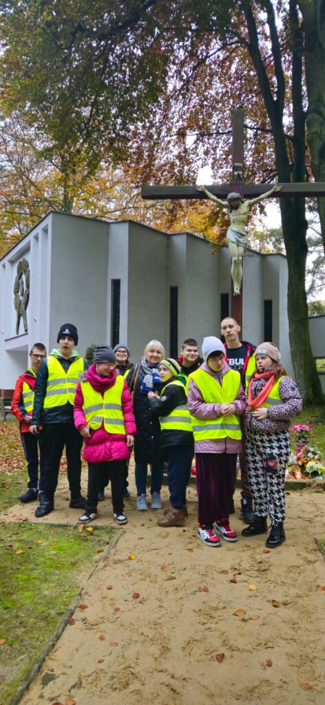 Uczniowie zapalają znicze na cmentarzu 