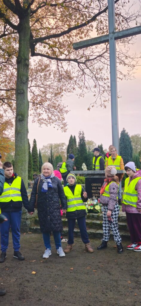 Uczniowie zapalają znicze na cmentarzu 